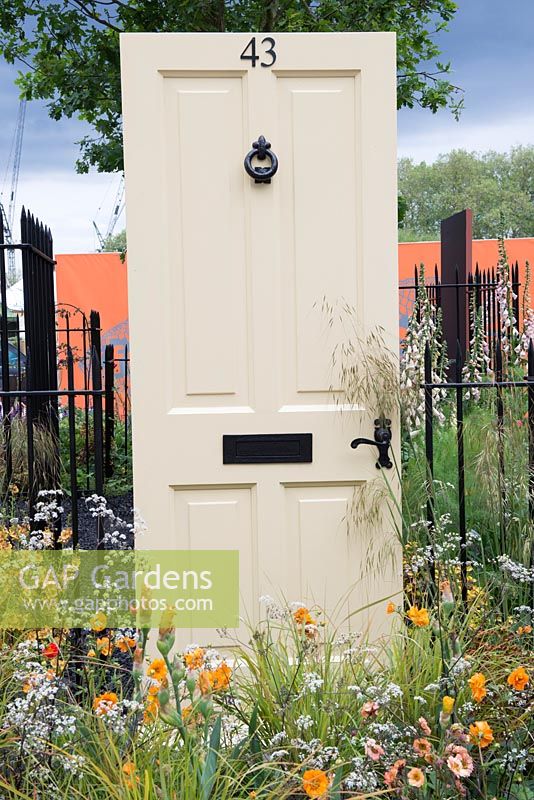 Cream painted front door surrounded by planting of Geum 'Fireball', Anthriscus sylvestris 'Ravenswing' and Stipa gigantea - The Modern Slavery Garden, RHS Chelsea Flower Show 2016, Design: Juliet Sargeant, Sponsor: The Modern Slavery Garden Campaign