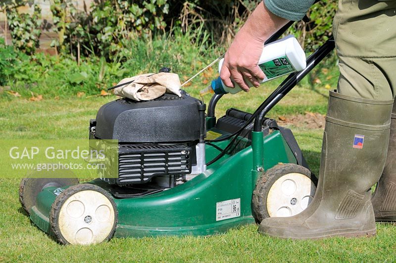 Four stroke petrol lawnmower, filling engine with fresh oil, UK, March