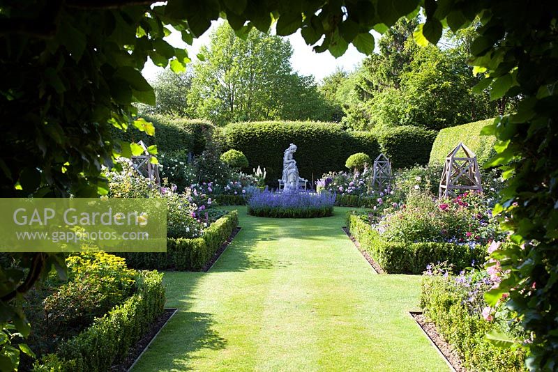 Formal rose garden enclosed by a Beech hedge, with Box borders and a stone statue, with Roses 'Sissinghurst Castle', 'Charles de Mills', 'Mary Rose', 'Munstead Wood', 'The Pilgrim', 'Fantin Latour', Rosa gallica var. officinalis, 'William Lobb', Rosa 'Complicata'