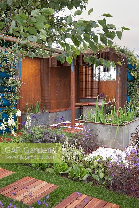 A contemporary corten steel summerhouse with integral benches and table and large metal rectangular containers. Rider on the Storm, RHS Tatton Flower Show 2011, Cheshire