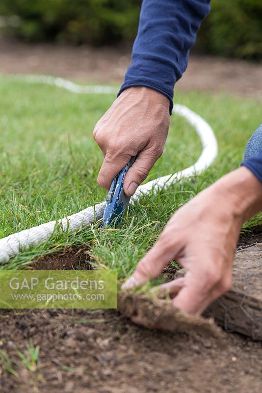 Using a stanley knife to cut newly laid turf to shape, following along the rope guide