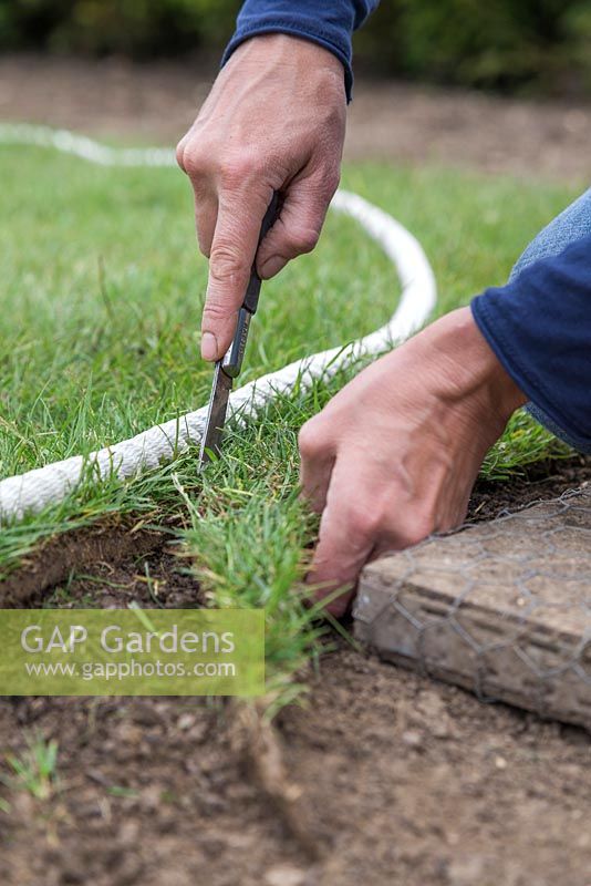 Using a knife to cut newly laid turf to shape, following along the rope guide