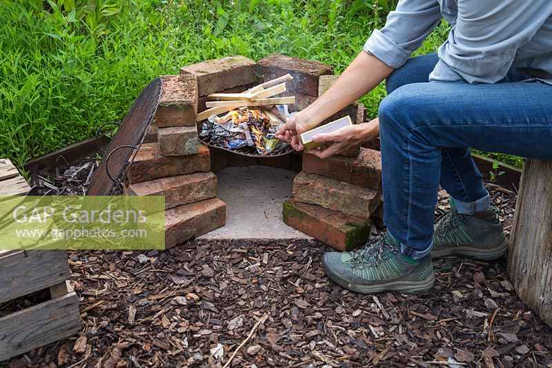 Using paper and kindling to create a fire within the barbecue