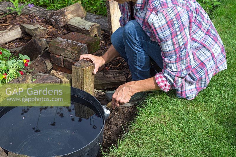 Place logs vertical around the barrel exterior to create rustic edging