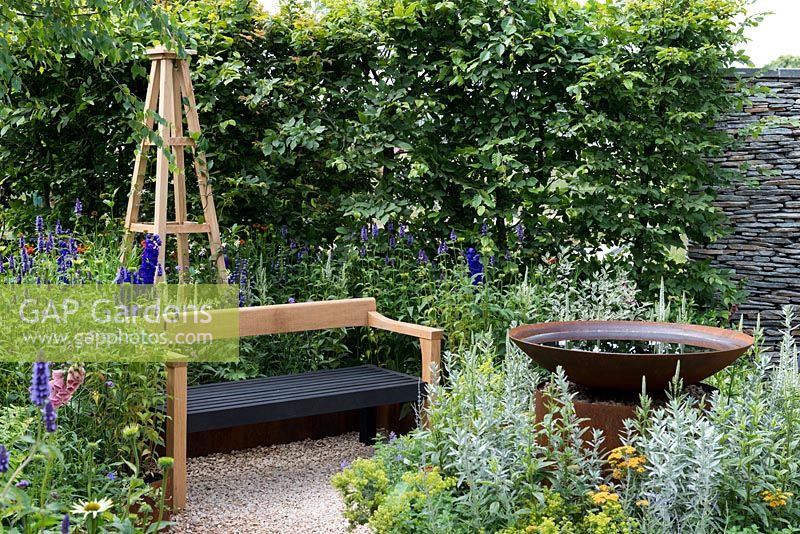 An Arts and Crafts inspired garden room with water feature, hornbeam hedge and hand crafted bench surrounded by perennials. A Summer Retreat designed by Laura Arison and Amanda Waring. RHS Hampton Court Flower Show 2016