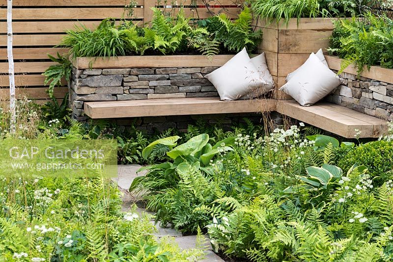 A woodland inspired city garden with floating wooden bench and raised dry stone beds planted with Dryopteris, Astrantia, Buxus and Hosta. Inner City Grace. Designed by Gary Price.