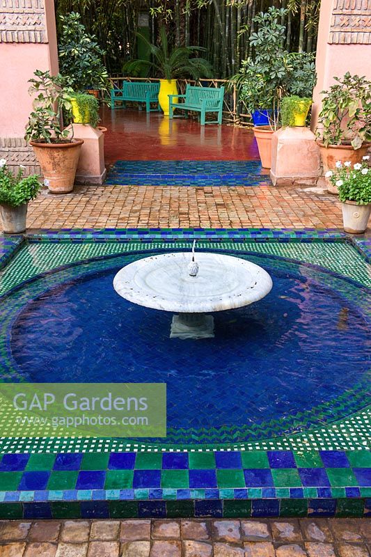 Low fountain and pool of water with blue and green glazed tiles in the Jardin Majorelle. Created by Jacques Majorelle and further developed by Yves Saint Laurent and Pierre Bergé, Marrakech, Morocco