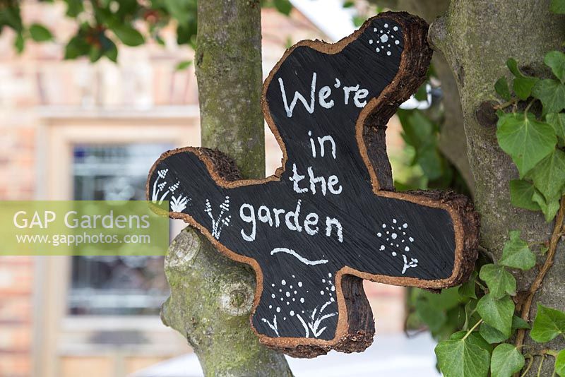 Oak tree slice painted and decorated to display 'We're in the garden'