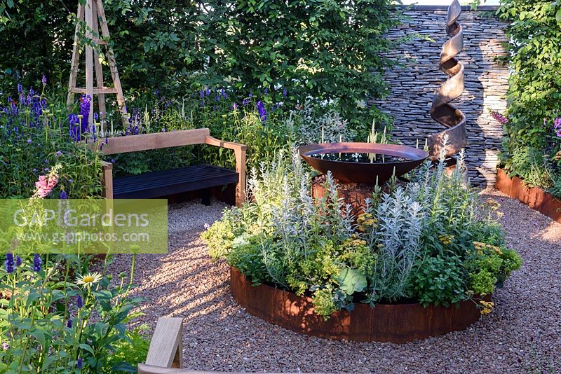 CCLA. A summer Retreat. Shallow Water Basin in circular bed, timber bench and gravel pathway Designers: Amanda Waring and Laura Arison Sponsors: CCLA. RHS Hampton Court Palace Flower Show 2016