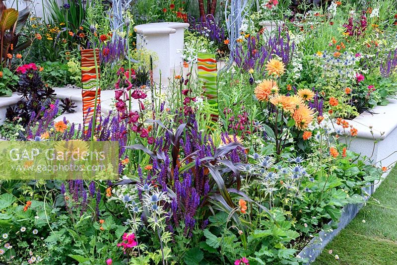 New Horizons City Garden. Coloured Fused glass panels in colourful border of orange,red and blues. Designers: Beautiful Borders, Sponsors: Beautiful borders Garden Design. RHS Hampton Court Palace Flower Show 2016