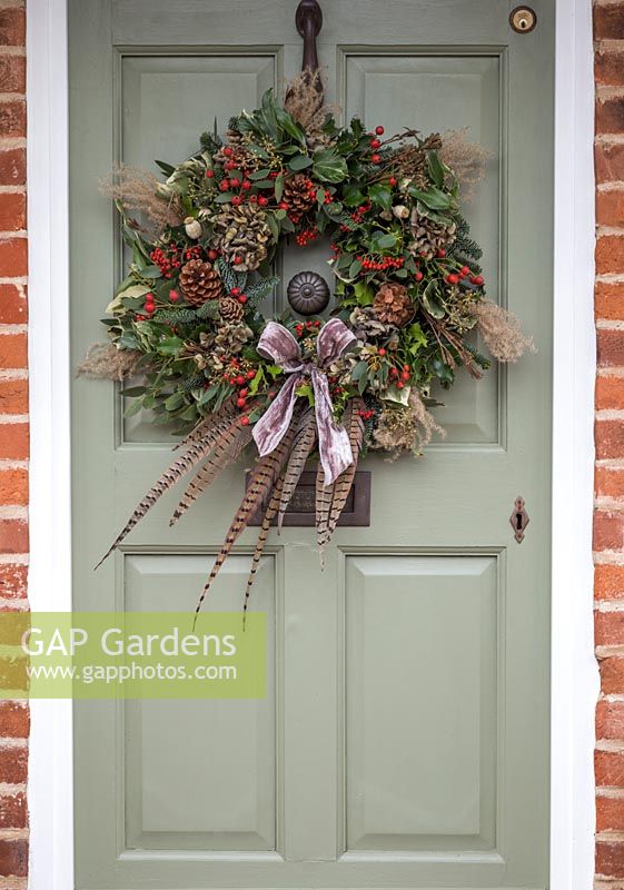 A traditional christmas wreath made with Eucalyptus gunnii, Rosa 'Bonica' rose hips, Variegated Ivy, Ilex aquifolium, Cotoneaster lacteus, Pinus nobilis, Godetia and Miscanthus sinensis seed heads