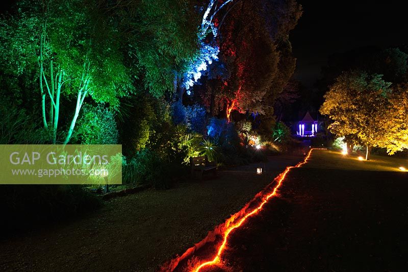 A rope of red light guides visitors through the illuminated garden with the Pavilion beyond