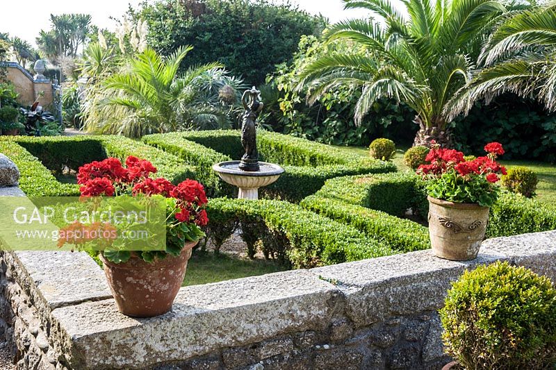 Box parterre with cental water feature and date palms.