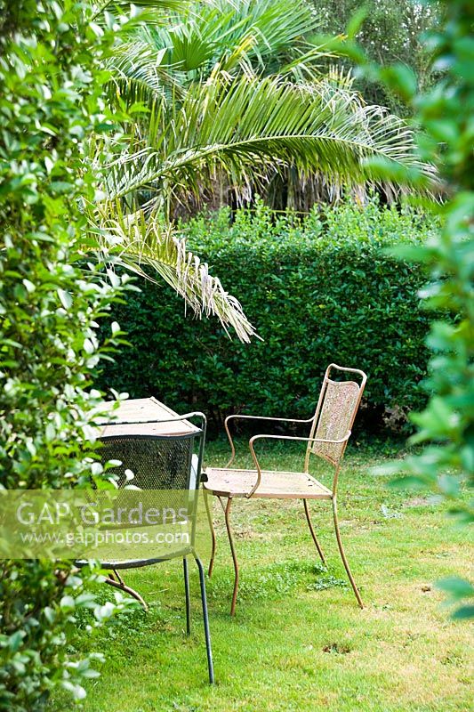 Metal table and chairs inside one of the gardens 'privet rooms' that give protection from the prevailing winds