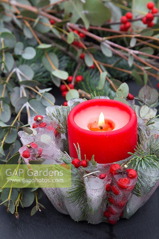 A frozen Jelly mould candle bowl with a lit candle. Constructed from Pine foliage, Eucalyptus and Ilex verticillata berries