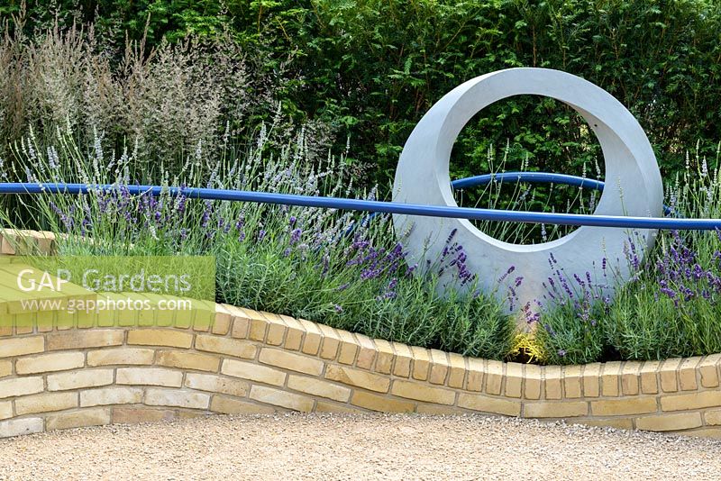 Blue curving handrails above brickbenches with Calamagrostis acutiflora 'Overdam', Lavandula 'Hidcote'. The Abbeyfield Society: a Breath of Fresh Air, RHS Hampton Court Palace Flower Show 2016. Design: Rae Wilkinson