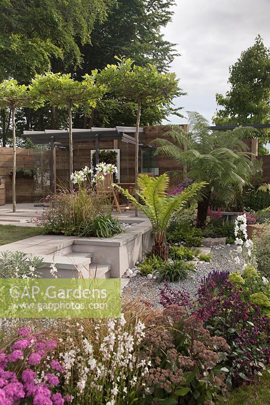 An outdoor kitchen with dining area and framed glass panels - Through The Looking Glass at RHS Tatton Park Flower Show 2016