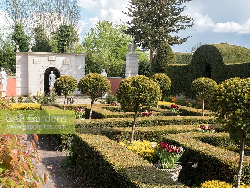 The Laskett Gardens- The Yew garden with its Taxus baccata hedges and topiary leading the eye to Nymphauem statues and wall in a clasical Greek style.  The wall is inscribed with Sir Roy Strongs initials and dates. Eagles adorn the two pillars.