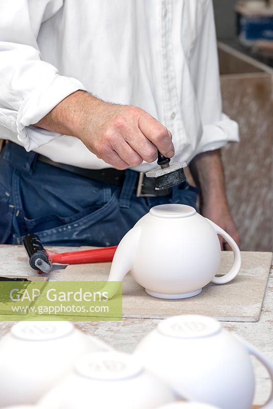 Stephen stamps the bottom of the teapot with the logo for Aston Pottery.