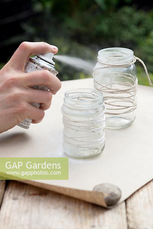 Making garden lanterns. Spray wrapped jar with the white paint using paper to protect surfaces