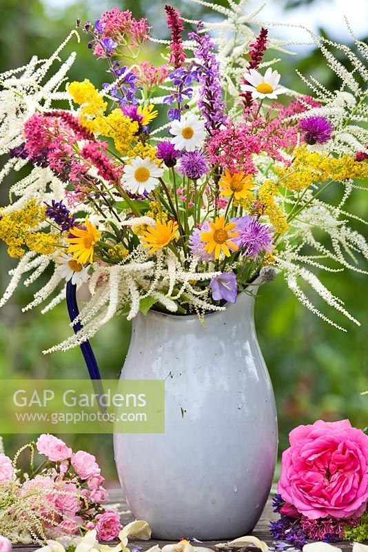 Jug of wildflowers. Leucanthemum, Salvia, Galium verum, yellow ox eye, red valerian, daisies, astilbe, persicaria Centaurea jacea.