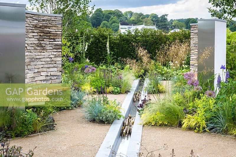 Dry stone wall, wooden bench seat, water feature rill channel and beds of herbaceous perennials, grasses, shrubs and trees - Cruse Bereavement Care: 'A Time for Everything' - RHS Chatsworth Flower Show 2017 - Designer: Neil Sutcliffe - Sponsor: London Stone