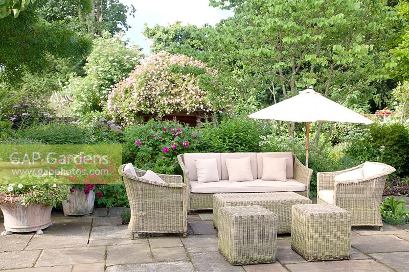 Wicker furniture on patio in summer with Rosa and mixed decorative containers