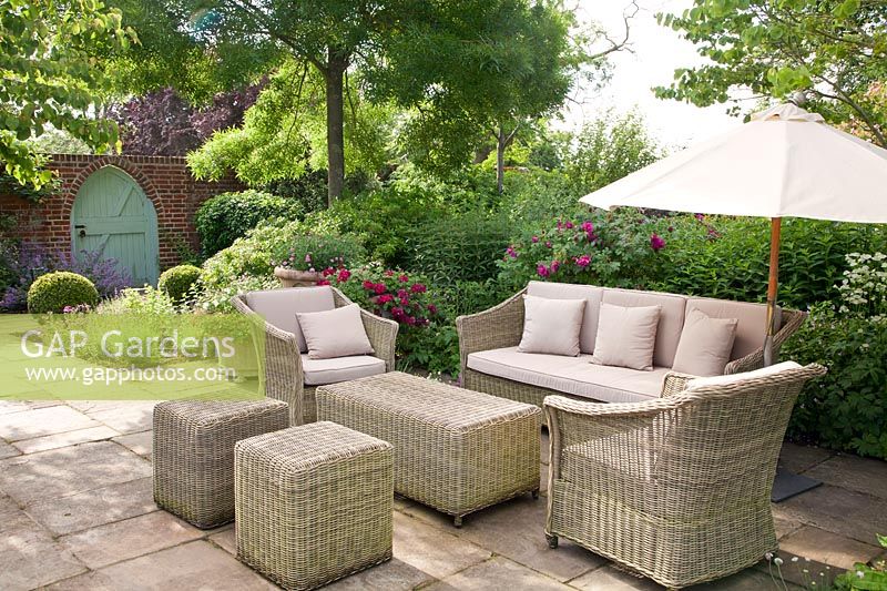 Wicker furniture on patio in summer with Rosa, clipped topiary and mixed decorative containers