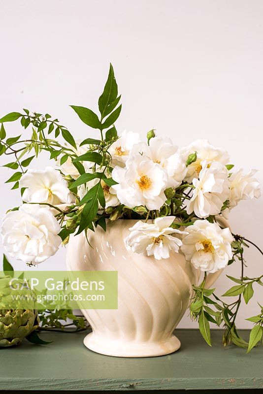 Flower arrangement with white roses, jasmine and ferns in cream china jug