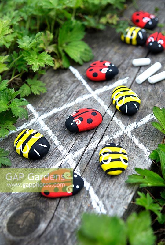 Garden craft making painted Bumble bees and Ladybirds with stones. Draw a noughts and crosses board with chalk and use the painted insects as game pieces