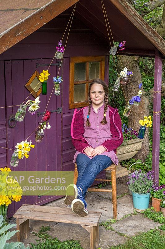 Young girl sat in front of decorated playhouse