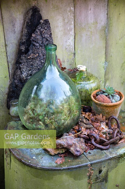 Glass bottle, terracotta pot and other arranged found objects at Charlotte and Donald Molesworth's garden, Kent, UK.