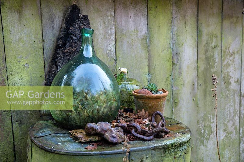 Glass bottle, terracotta pot and other arranged found objects at Charlotte and Donald Molesworth's garden, Kent, UK.