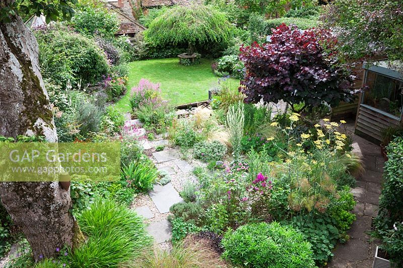 Overhead view of a small low maintenance modern cottage garden. York stone and gravel pathway meander through planting with Stipa tenuissima, Hakonechloa macra 'Aureola', Stipa arundinacea, Verbena bonariensis, Thyme, Verbascum, Fennel, Lychnis coronaria, Cercis canadensis 'Forest Pansy' to the weeping Birch - Betula pendula 'Youngii'.