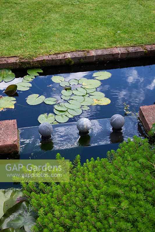A lead covered water feature two tier pond with water lily foliage