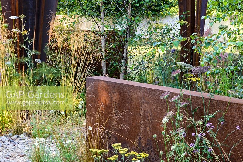 Corten steel structures designed by sculptor Simon Probyn with Betula pendula, Buddleja davidii 'Wisteria Lane' and perennials including Achillea 'Moonshine' and Pilosella aurantiaca - Brownfield Metamorphosis. RHS Hampton Court Palace Flower Show 2017 - Designer: Martyn Wilson. Sponsor: St. Modwen Properties PLC