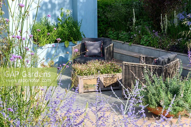 Paved seating area with Linaria purpurea 'Canon Went' in a shallow container, border with Stipa gigantea and Verbena bonariensis - Viking Cruises World of Discovery Garden, RHS Hampton Court Palace Flower Show 2017 -Designer: Paul Hervey-Brookes