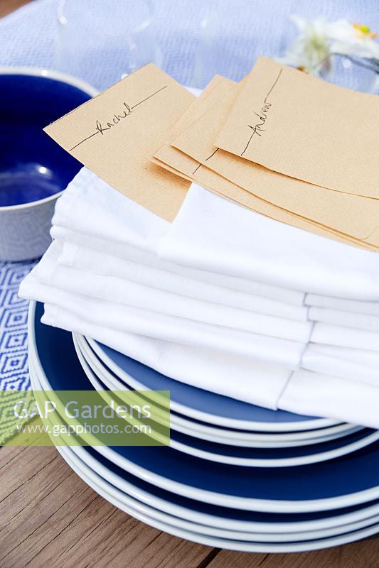 Blue crockery and white napkins with pockets folded to put a name card in them for dressing the table