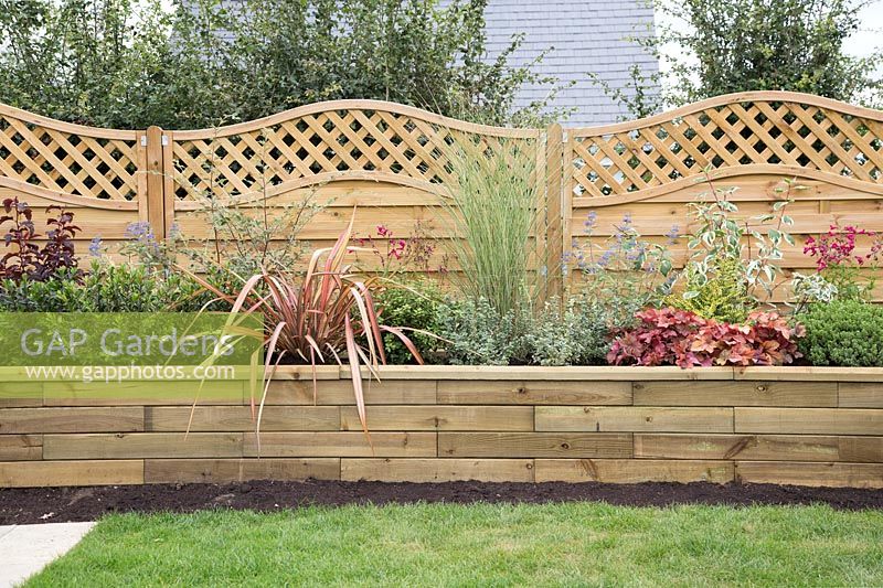 Raised bed with shrub and perennials supplied by Gardens on a Roll