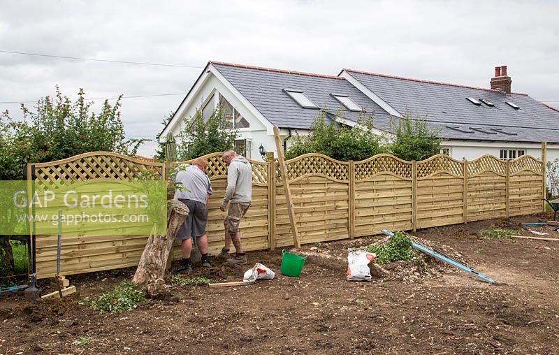 Men levelling fencing panels to ensure straight line
