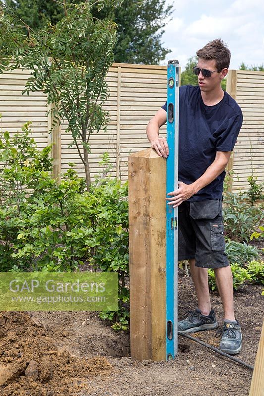 Man using spirit level to ensure gate post is straight