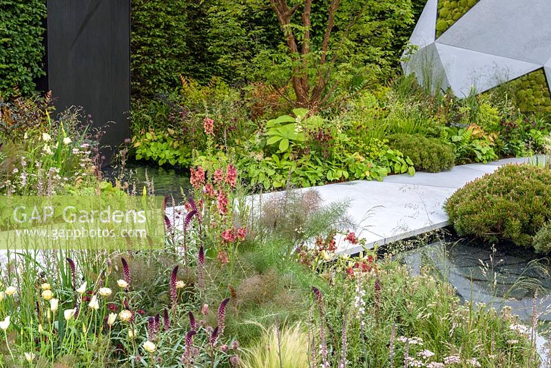 Stream running beneath  stone path with mixed planting - The Jeremy Vine Texture Garden - Radio 2 Feel Good Gardens -RHS Chelsea Flower Show 2017 - Designer: Matt Keightley