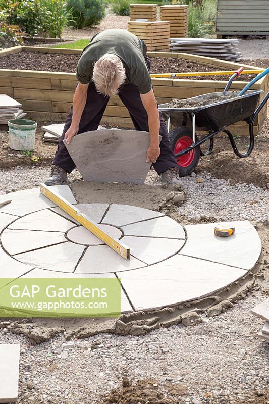 Man laying slabs in centre of circular patio