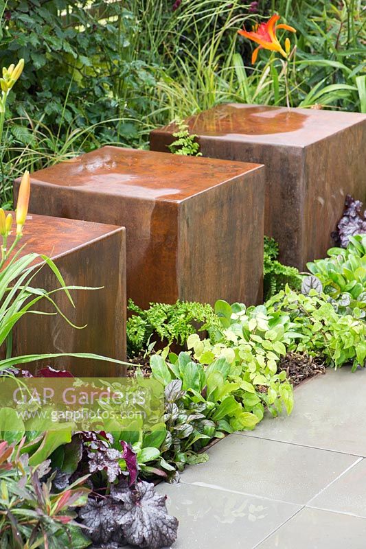 Metal seats amongst planting - Foundations for Growth Garden at RHS Hampton Court Palace Flower Show 2015