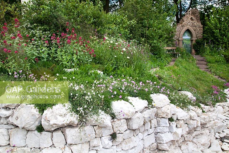 Welcome to Yorkshire Garden - A view of the bench and the ruined sandstone abbey, surrounded by digital purpurea, leucanthemum vulgare, meadow cranesbill, sea thrift and many wild herbs and flowers, from the sandstone cliffs - RHS Chelsea Flower Show 2017