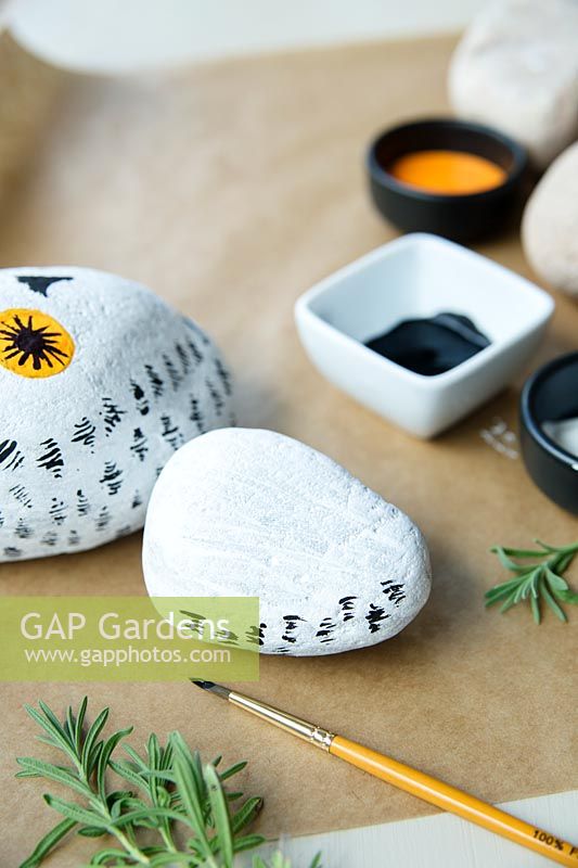 Making a stone owl decoration - once the white base paint is dry, paint little black feather marks on the body of the owl