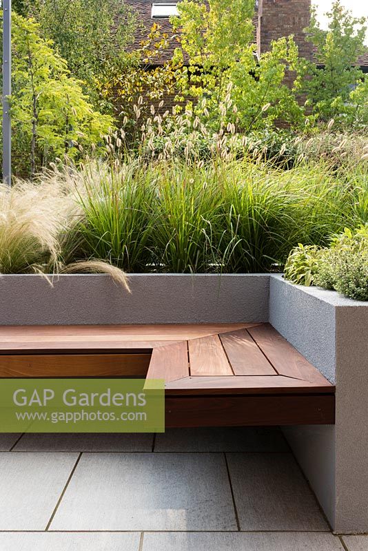Contemporary seat and raised bed with Stipa tenuissima, Pennisetum thunbergii 'Red Buttons', Salvia officinalis 'Kew Gold', Thymus 'Silver Queen', Molinia caerulea 'Karl Foerster'