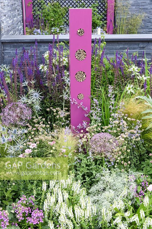 Bug hotel and planting in pink, blue and white with Salvia, Stipa and Allium with slate wall  - BBC Gardener's World Live, Birmingham 2017 - The Lanwarne Landscapes 'Contemporary Bee and Butterfly' Garden - Head Sponsors: IntoUniversity, Big City Bright Future Programme, Black Rock - Best Landscape Construction. Best Construction Landscaper