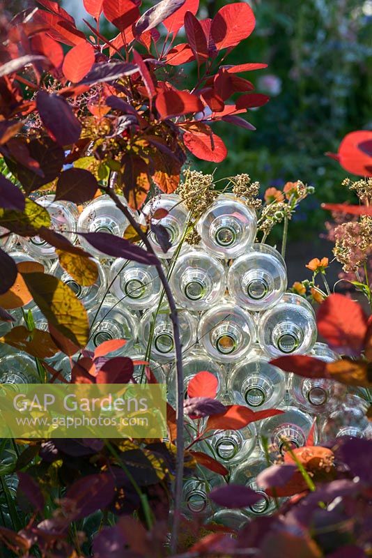 Recycled plastic bottles and red Cotinus. Forward and Back, Beautiful Borders in BBC Gardener's World Live, Birmingham 2017. Designer: Justine Wood, Sponsor: Friels Vintage Cider, Event Flag Hire, Sherwoods