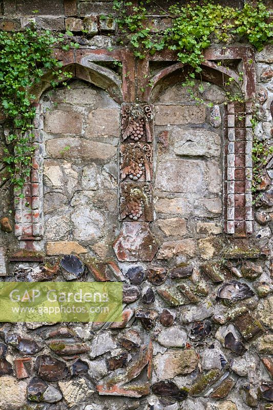 Part of 'Medieval' wall incorporating pseudo-ecclesiastical 'alcoves' and ornamental bricks and  flints. Trailing plant is Cymbalaria muralis - Kenilworth Ivy.